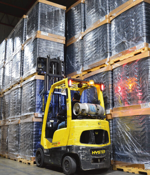 Warehouse male worker on forklift next to stacked pallets
