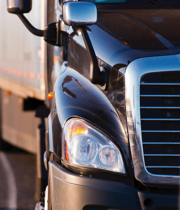 Close up details of black semi truck on the road on blurred trailer background