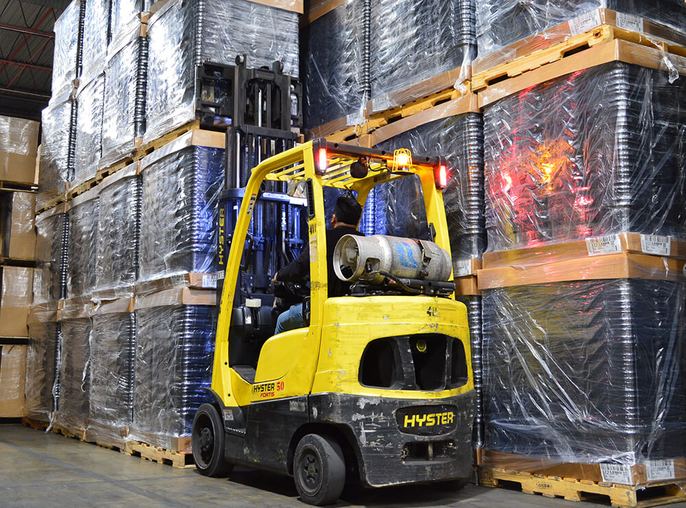Active yellow forklift inside of warehouse, lifting pallet