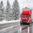 Red semi truck driving in snowy weather