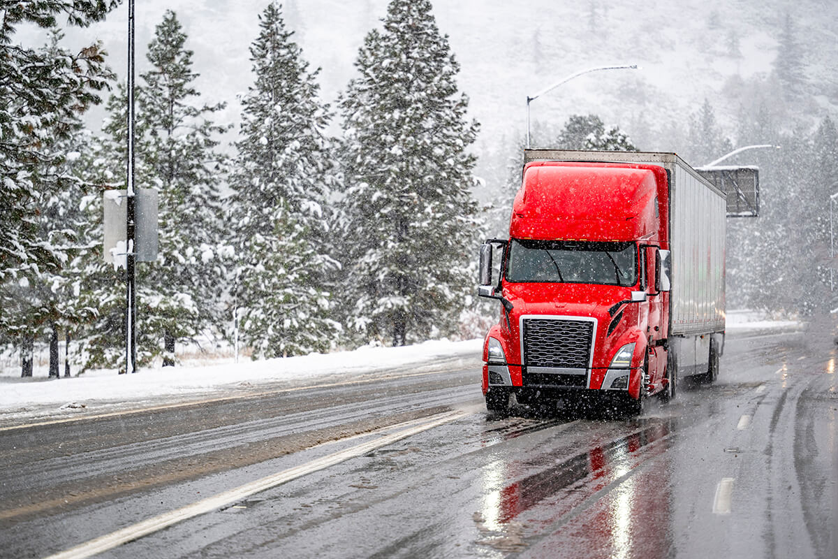 Red semi truck driving in snowy weather